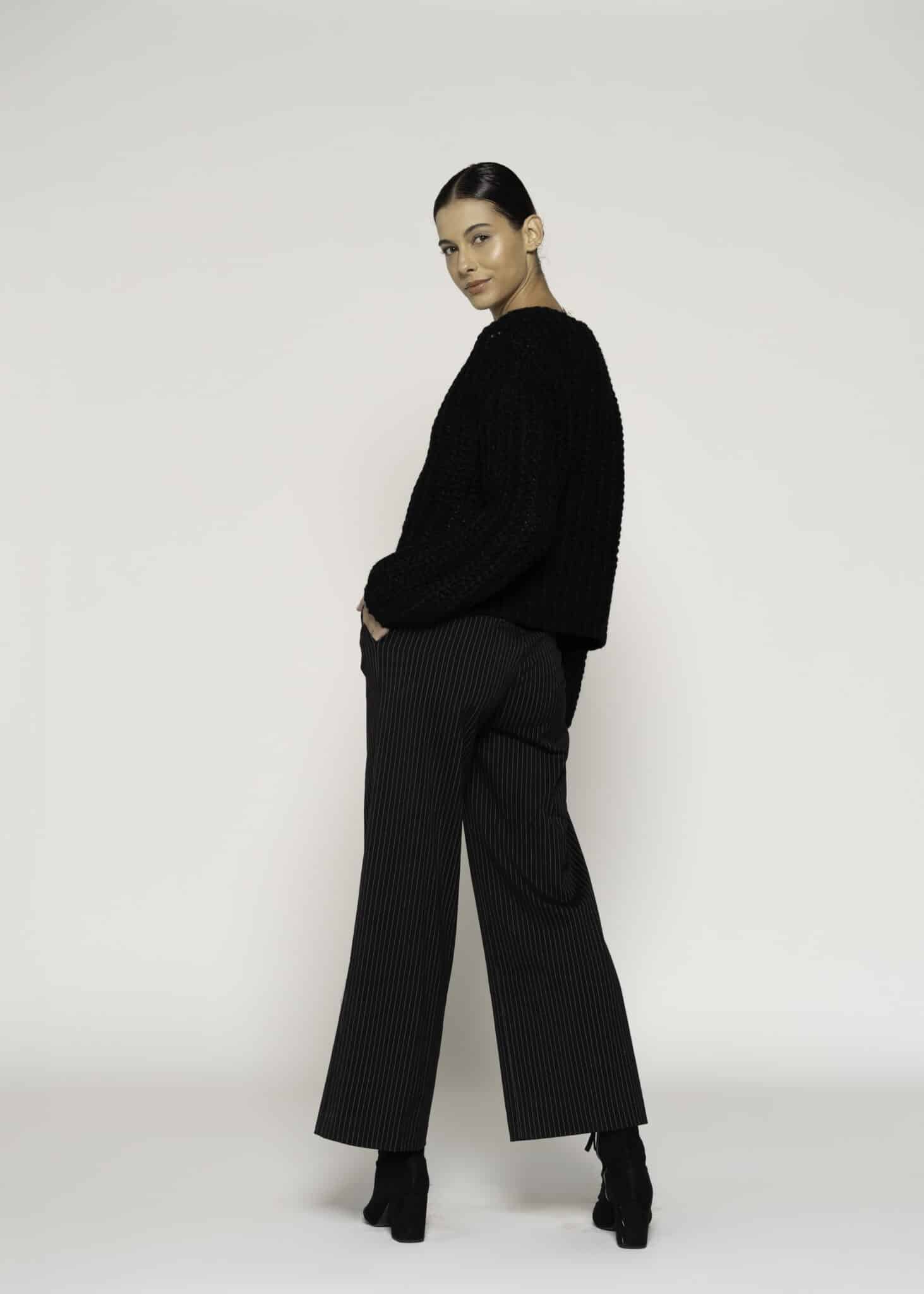 Chaqueta tejida negra con textura bouclé y cuatro botones dorados, modelo Formentera, frente.
